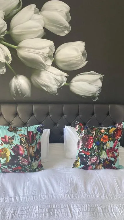 Bed with floral patterned pillows and white tulip artwork headboard