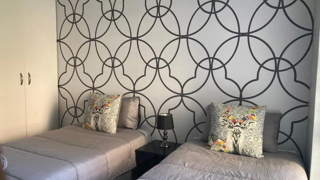Twin bedroom with patterned headboard and decorative pillows