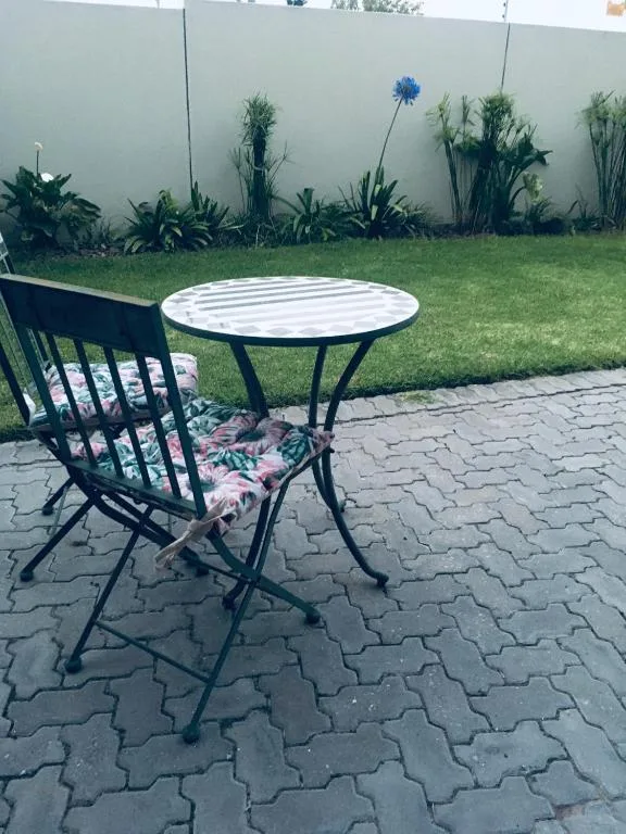 Outdoor patio seating area with round table and chair overlooking manicured garden