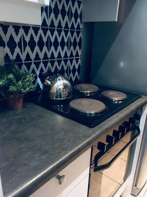 Modern kitchen with black cooktop, geometric tile backsplash, and marble counters