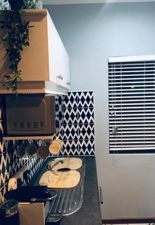 Compact kitchen with microwave, geometric backsplash, and cooking utensils