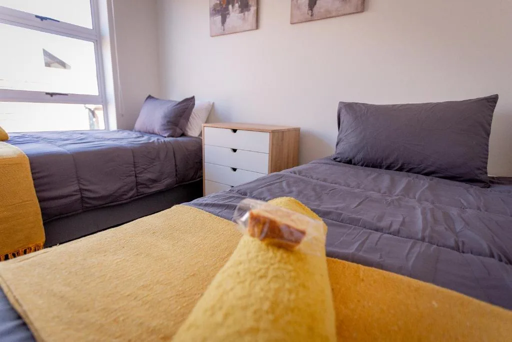 Bright bedroom with two beds, natural light, and modern furnishings