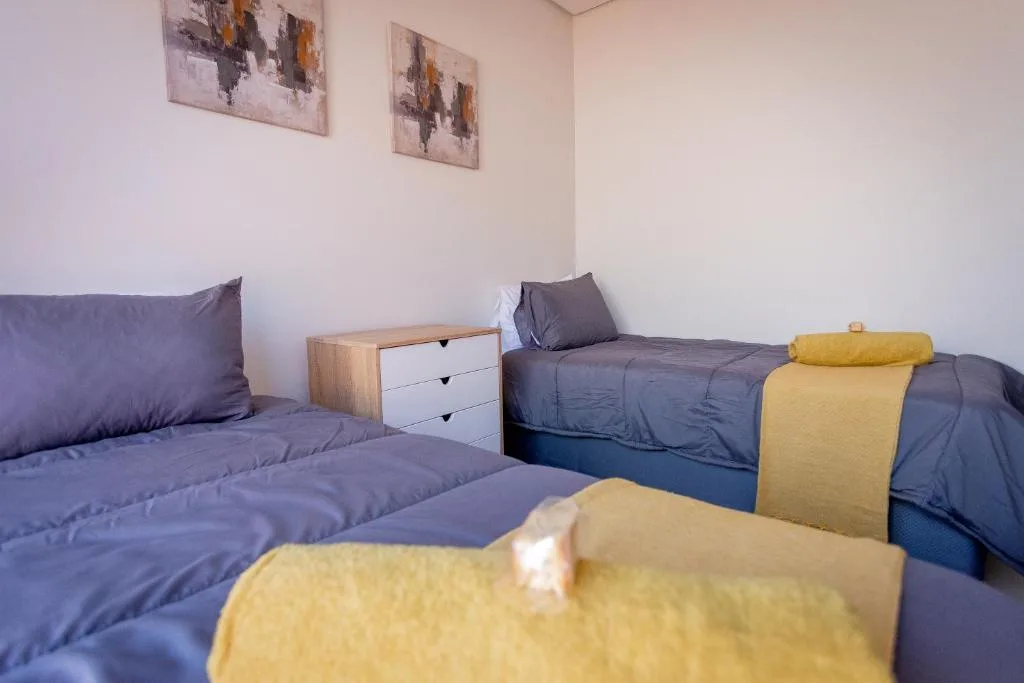 Bright bedroom with two single beds, wooden nightstand, and wall art