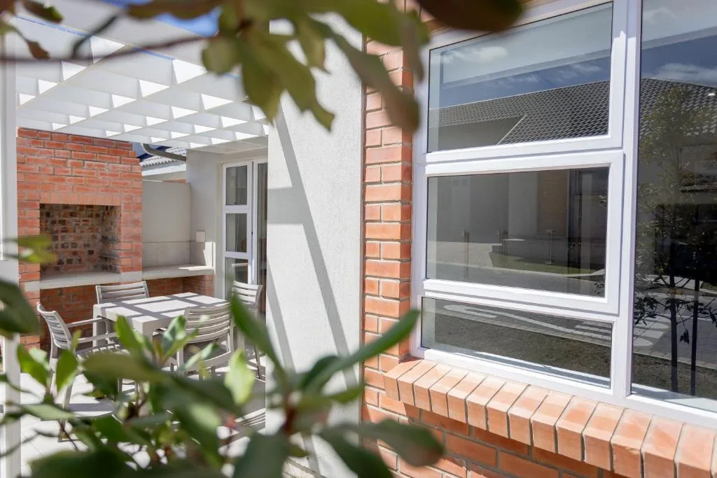 Covered patio with dining chairs and brick fireplace, modern windows