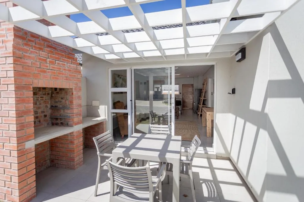 Covered patio with dining table, chairs, and brick fireplace