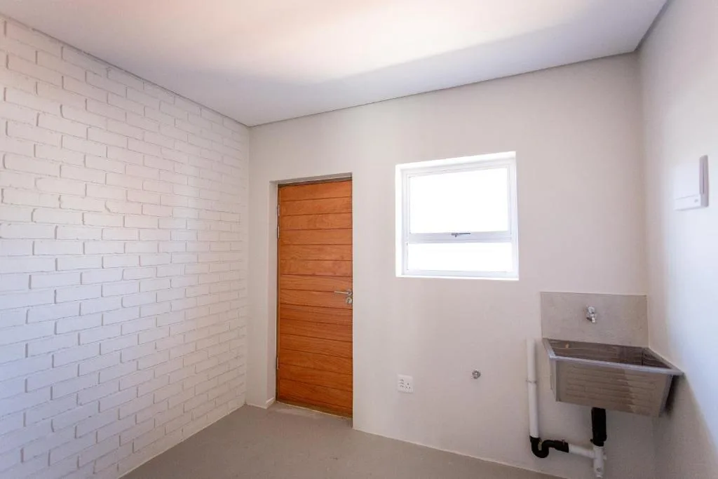 Utility room with laundry sink, wooden door, and window opening