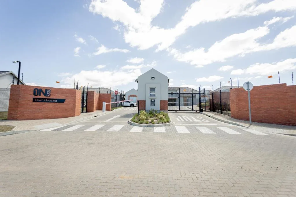 Modern gated housing development entrance with brick walls and central guardhouse