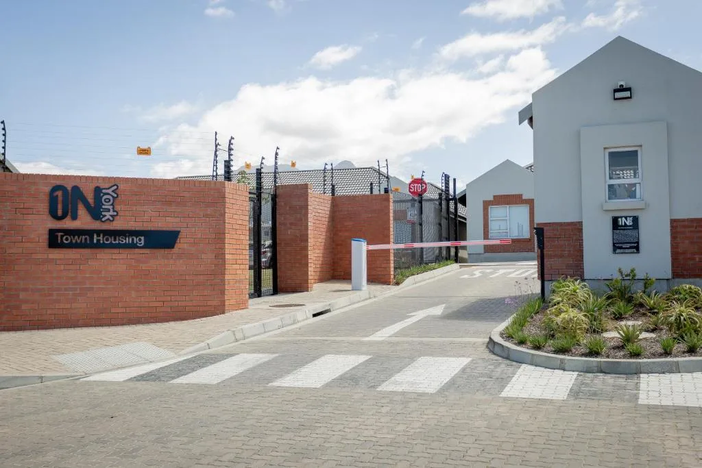 Modern white and brick townhouse entrance with paved driveway and landscaping