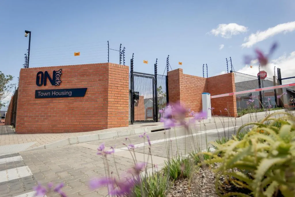 Modern brick building entrance with secure gate and landscaped garden beds