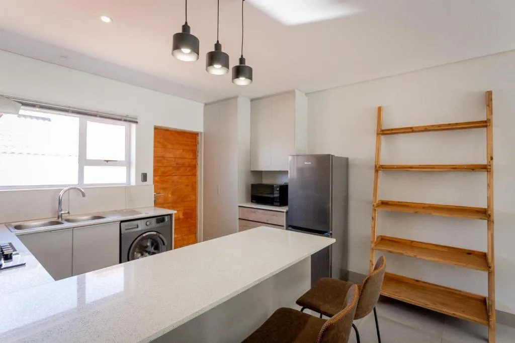 Modern kitchen with white counters, stainless steel appliances, and pendant lighting