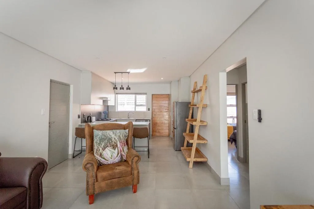 Open-plan lounge with leather armchair, kitchen visible, modern apartment interior