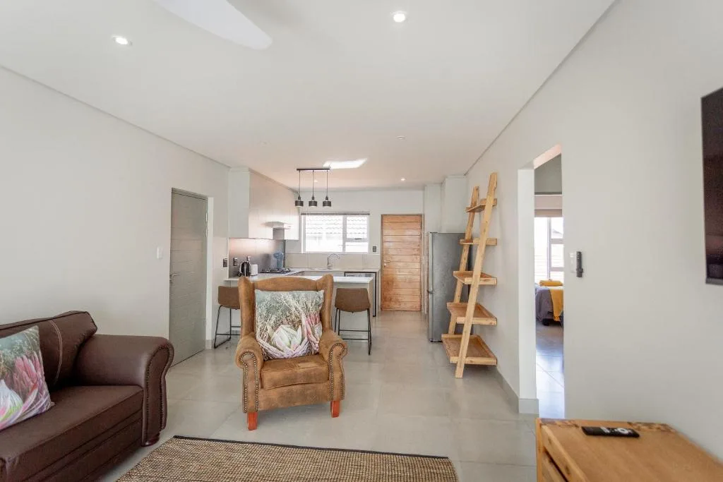 Modern lounge with brown sofa, wooden chair, and open-plan kitchen