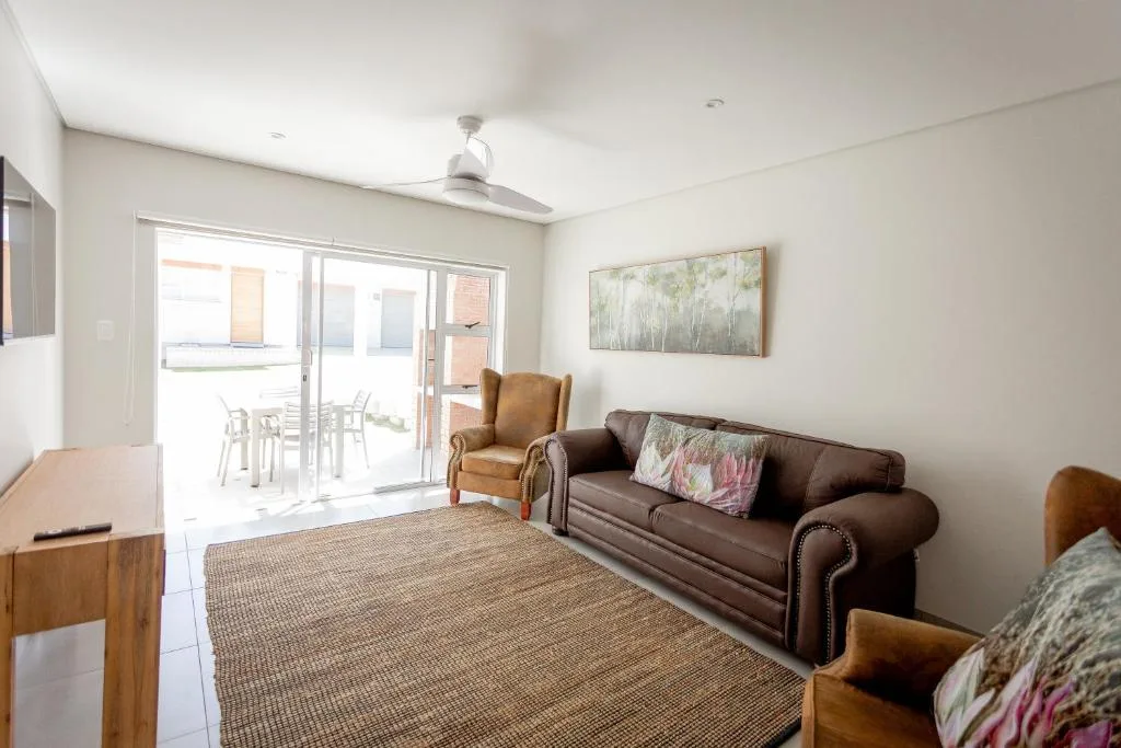 Spacious living room with brown sofa, armchairs, and access to outdoor deck