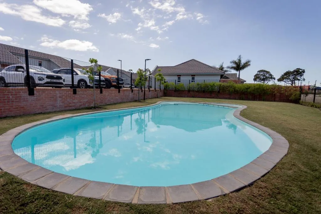 Sparkling turquoise swimming pool with manicured lawn and modern house backdrop