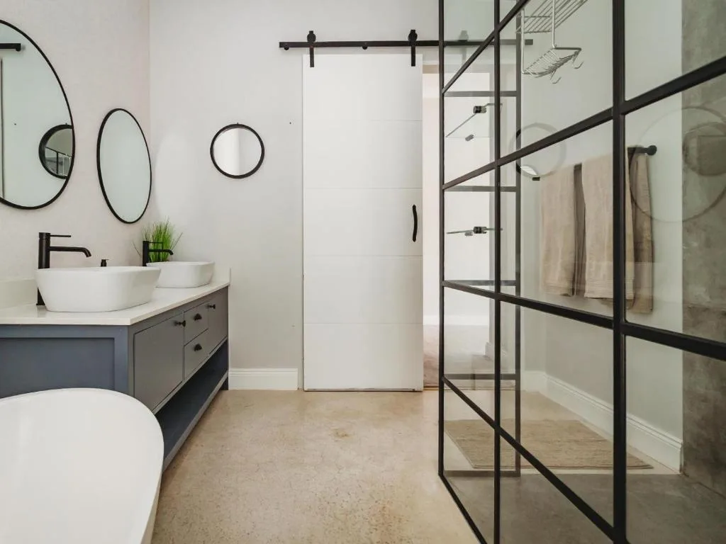 Modern bathroom with vanity sink, circular mirrors, and glass shower enclosure
