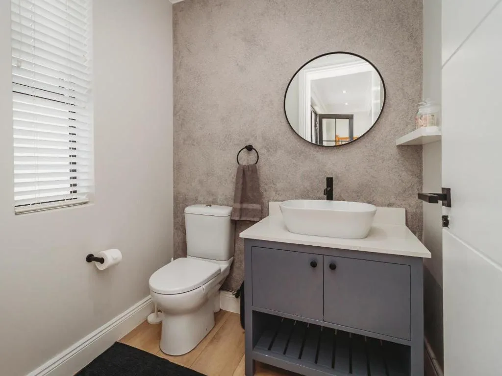 Modern bathroom with vessel sink, toilet, and round mirror