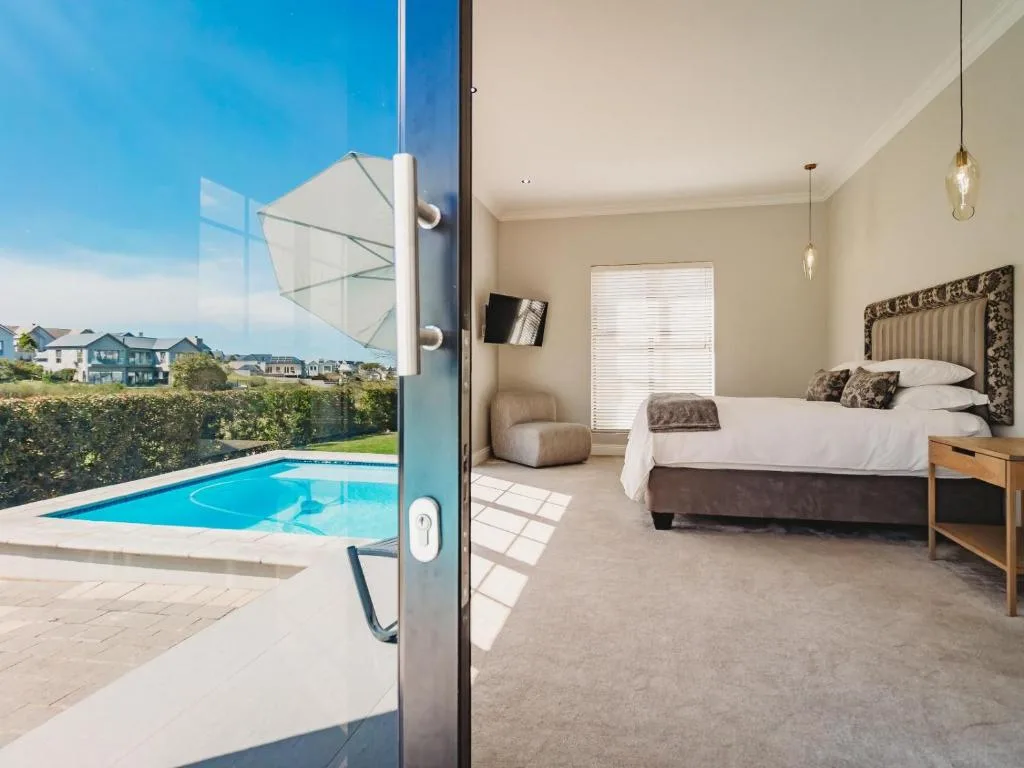 Spacious bedroom with pool view through glass doors and modern furnishings
