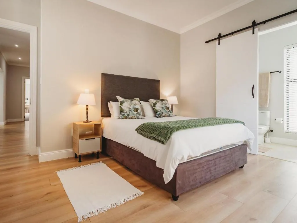 Spacious bedroom with dark upholstered bed, white bedding, and green accents
