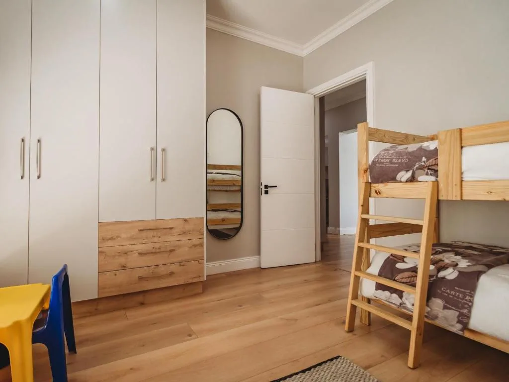 Bright bedroom with wooden bunk beds and white built-in wardrobes