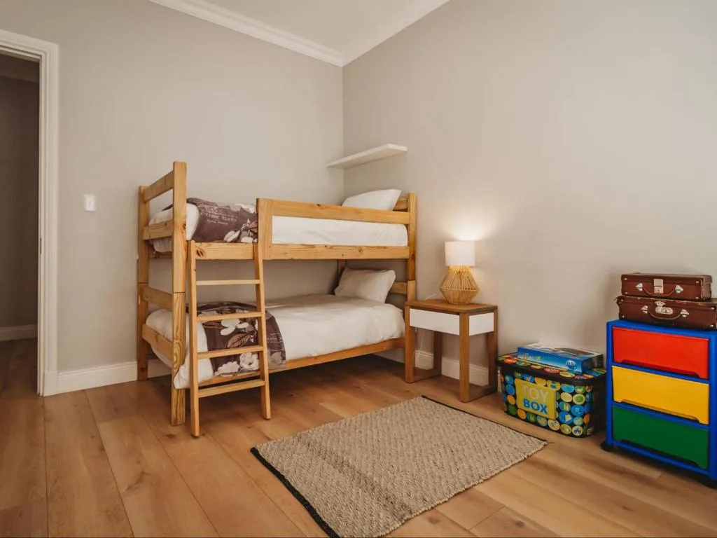 Wooden bunk beds in a bright, clean children's bedroom with wooden floors