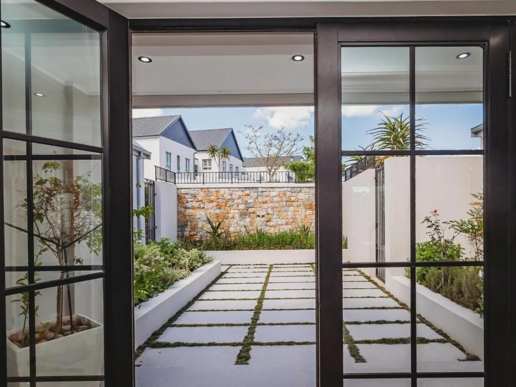 Modern patio with stepping stones and manicured garden facing stone wall