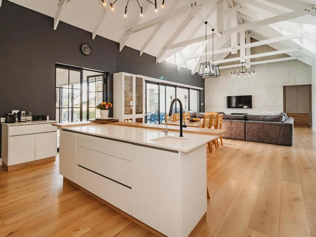 Modern open-plan kitchen with white cabinetry, island bench, and charcoal accent wall