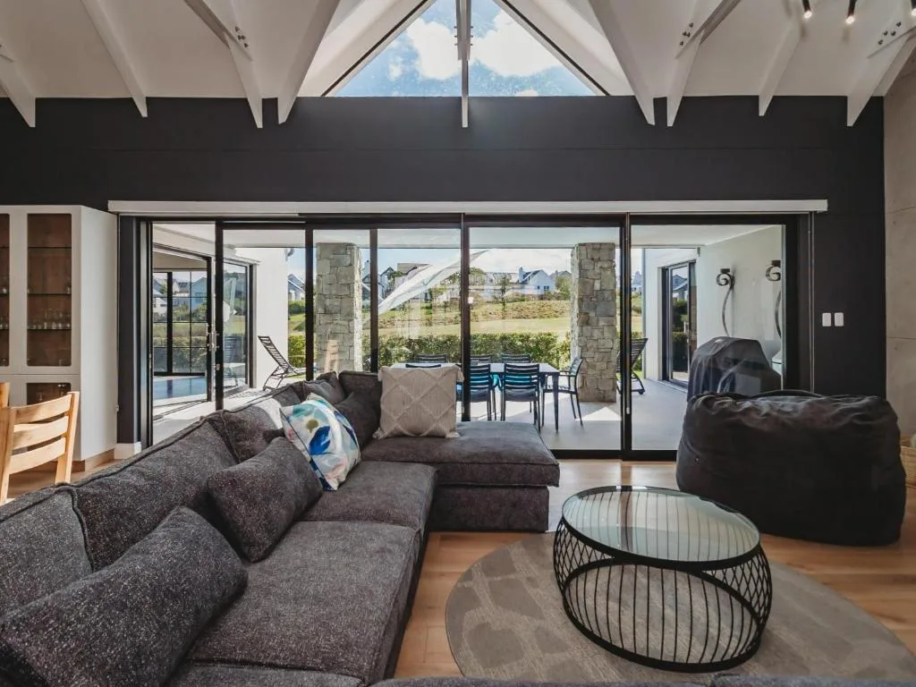 Modern lounge with gray sofa and bean bags, opening to deck with mountain views