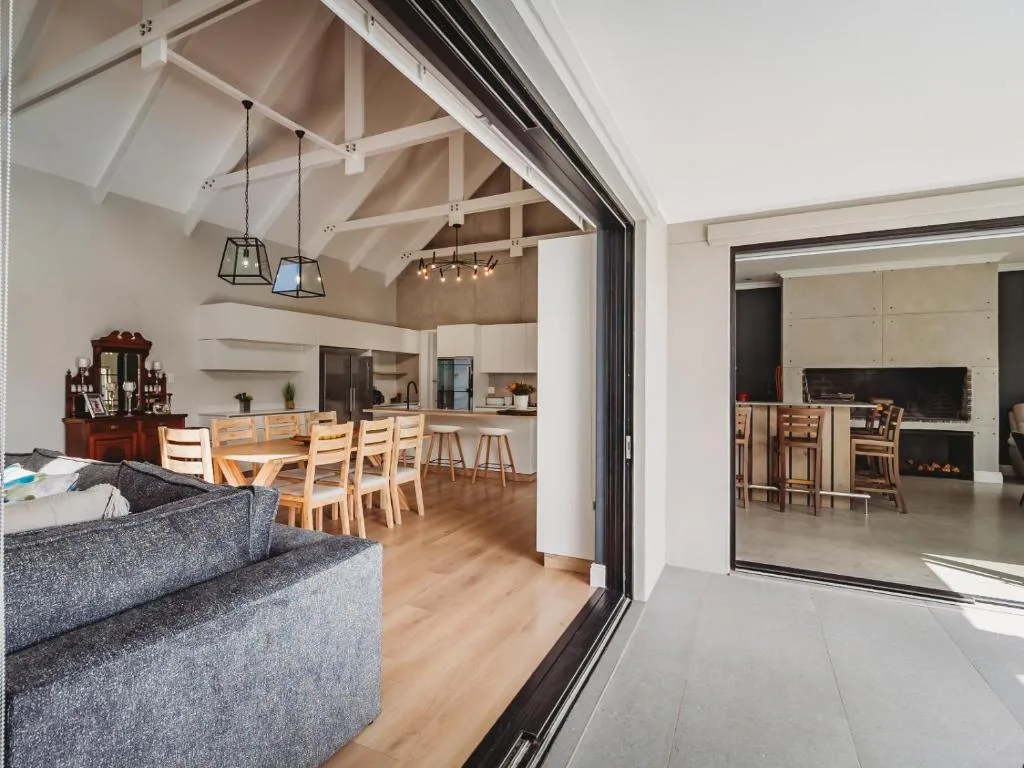 Open-plan lounge with gray sofa, dining table, and kitchen visible beyond