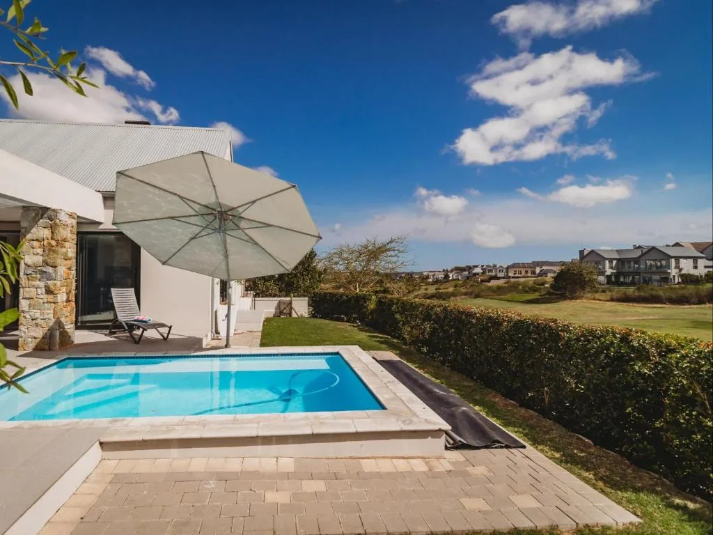Swimming pool with umbrella and lounger overlooking green gardens