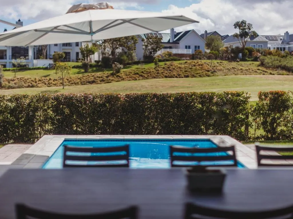 Modern swimming pool with loungers overlooking manicured garden grounds
