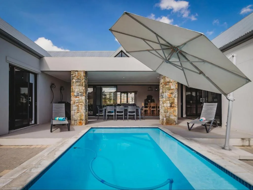 Sparkling swimming pool with modern house and shaded seating area