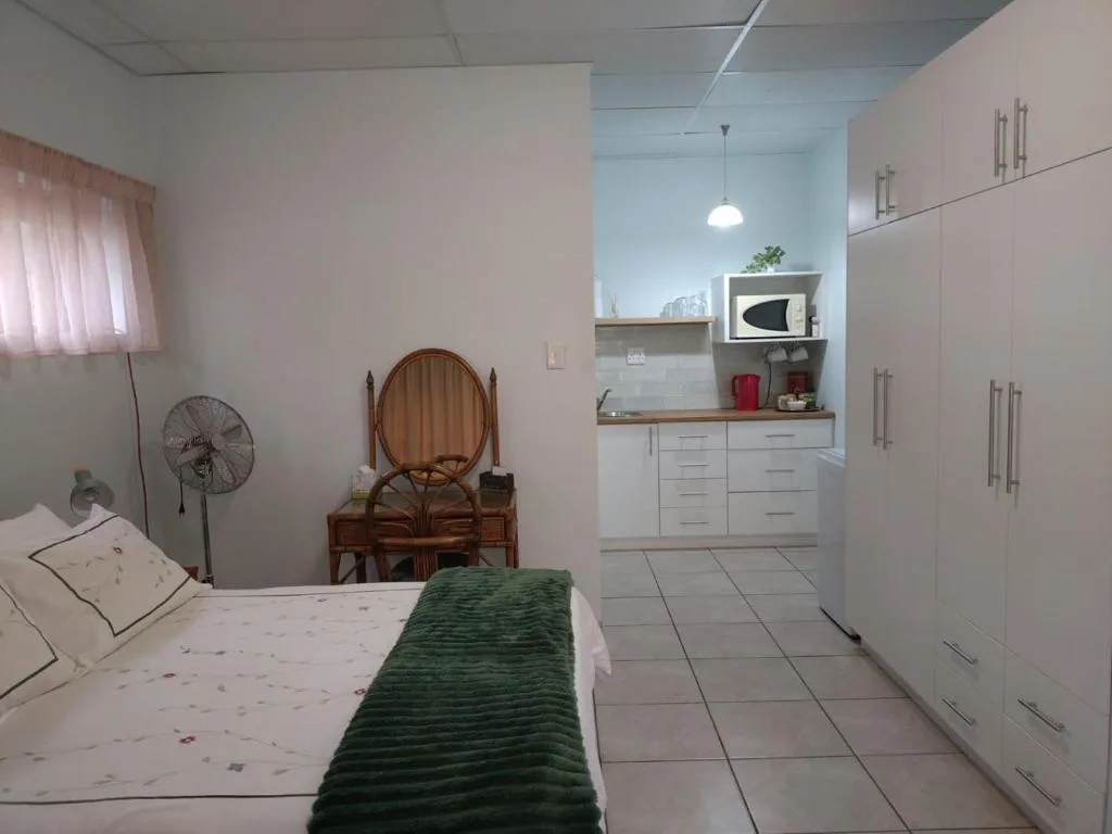 Bedroom with bed, vanity mirror, kitchenette, and built-in wardrobes