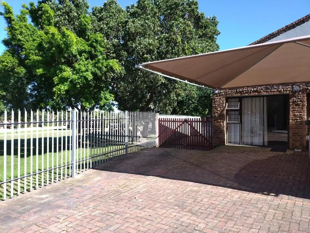 Brick cottage entrance with white picket fence and shade sail
