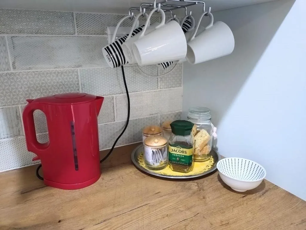 Kitchen counter with red kettle, coffee station, mugs and amenities