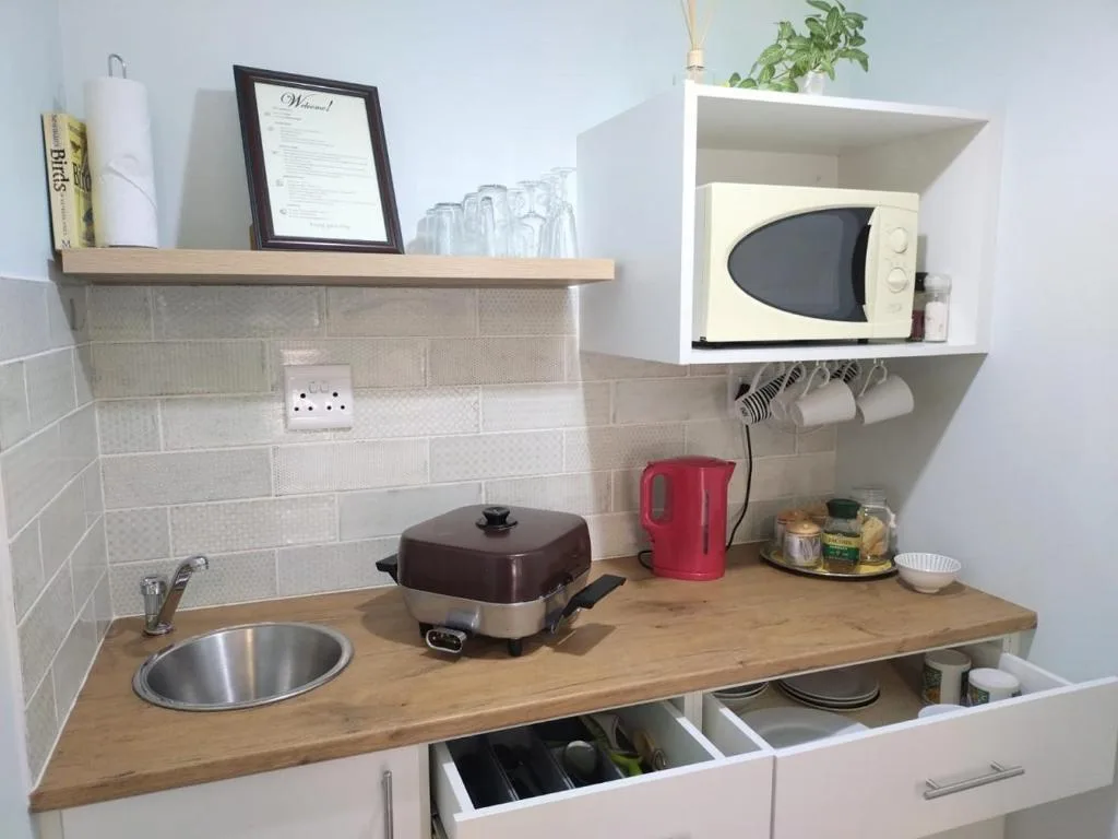 Compact kitchenette with wooden countertop, white subway tile backsplash, microwave, and storage