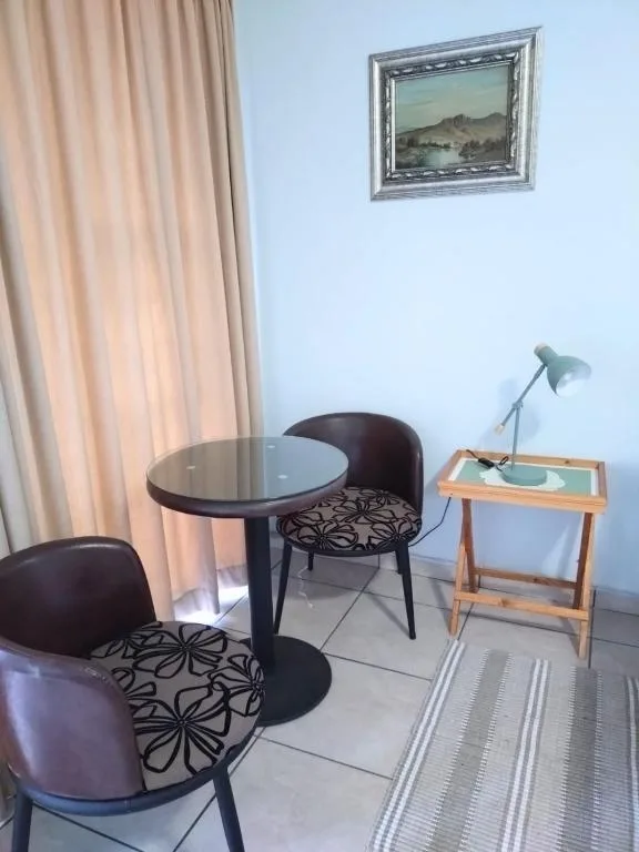 Compact lounge area with round table, patterned chairs, and desk lamp