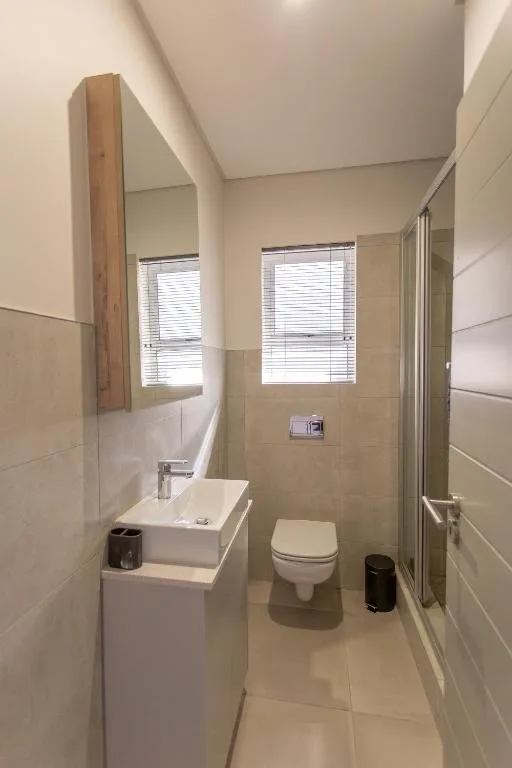 Modern bathroom with shower, toilet, vanity sink, and windows