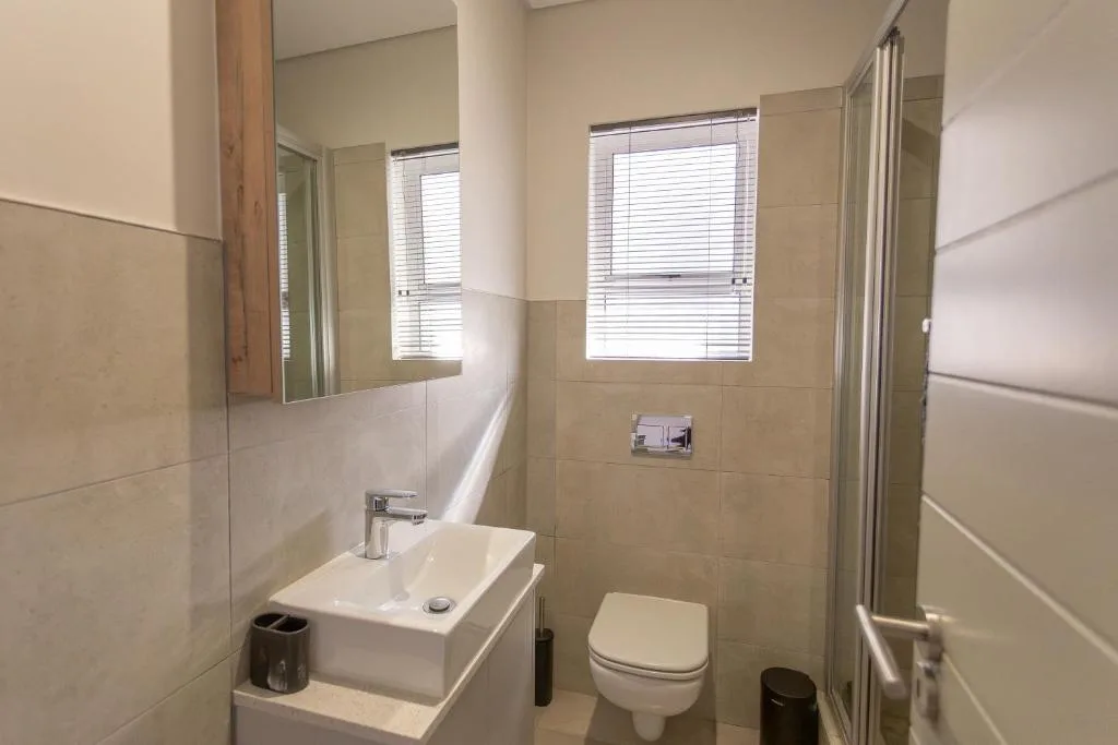 Modern bathroom with vanity sink, toilet, and walk-in shower enclosure