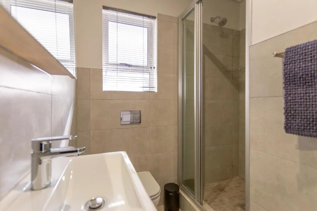 Modern bathroom with walk-in shower, vanity sink, and window