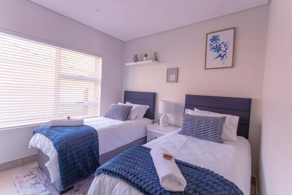 Twin bedroom with dark headboards, blue quilts, and pink walls