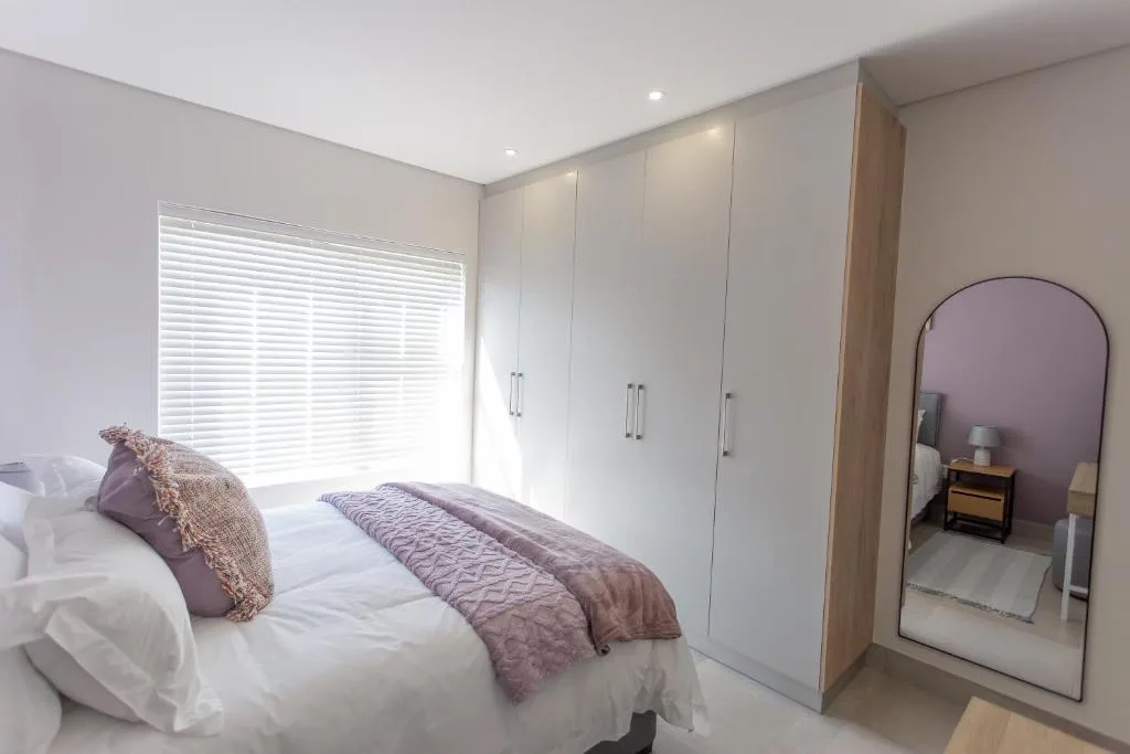 Spacious modern bedroom with queen bed, built-in wardrobes, and large windows