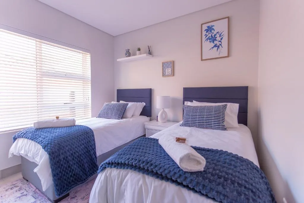 Twin bedroom with navy headboards, blue quilts, and coastal-themed wall decor