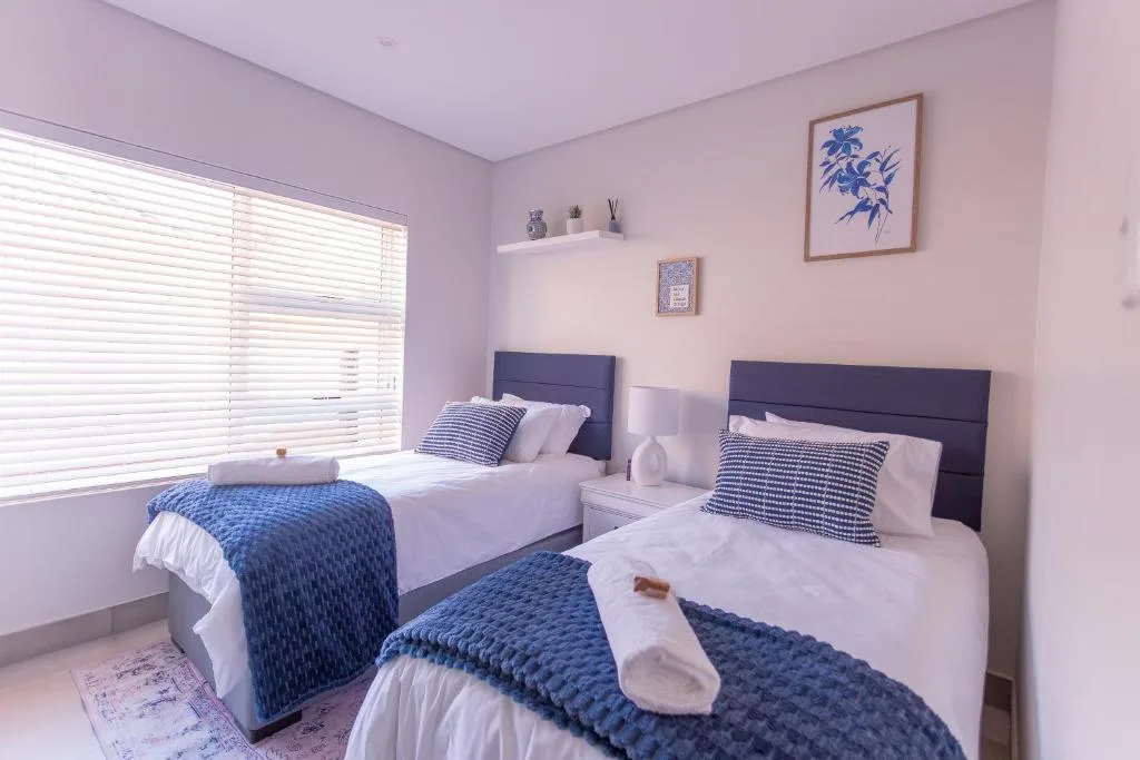 Twin bedroom with navy headboards, blue quilts, and soft pink walls