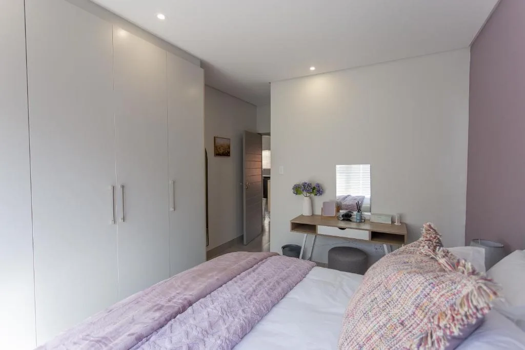 Modern bedroom with purple accents, built-in wardrobe, and vanity desk