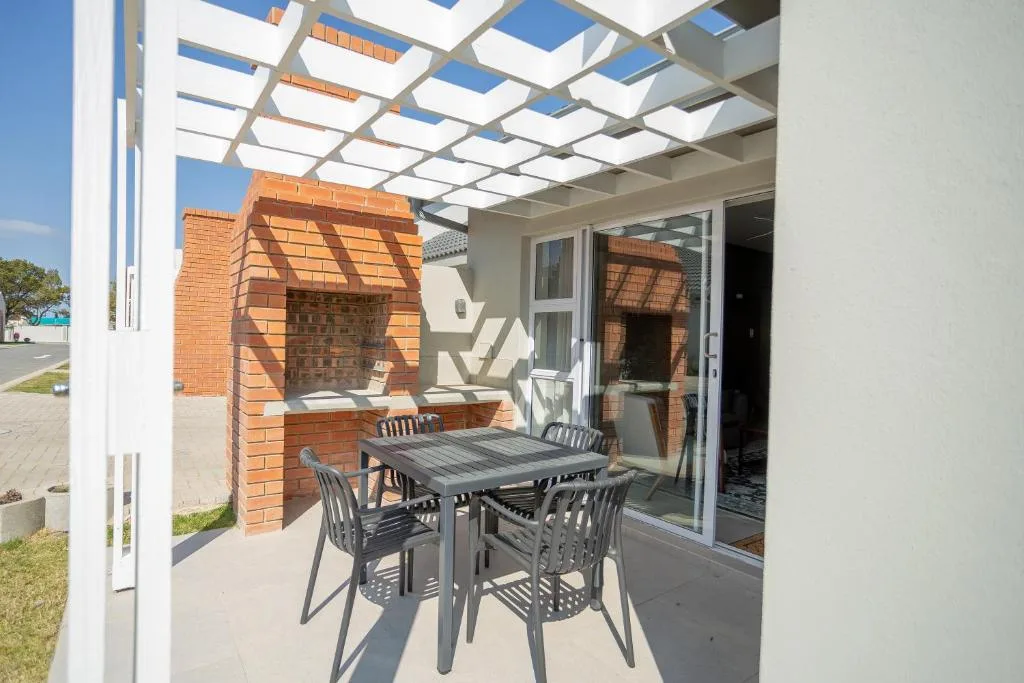 Covered patio with dining table, brick fireplace, and garden views