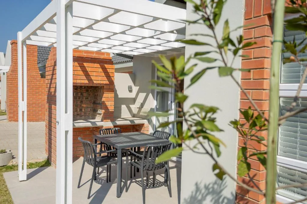 Outdoor patio with dining table under white pergola and garden plants