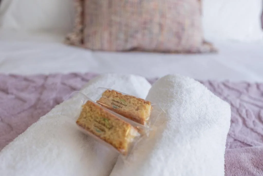 Luxury toiletries and fluffy white towel on bed with decorative pillows