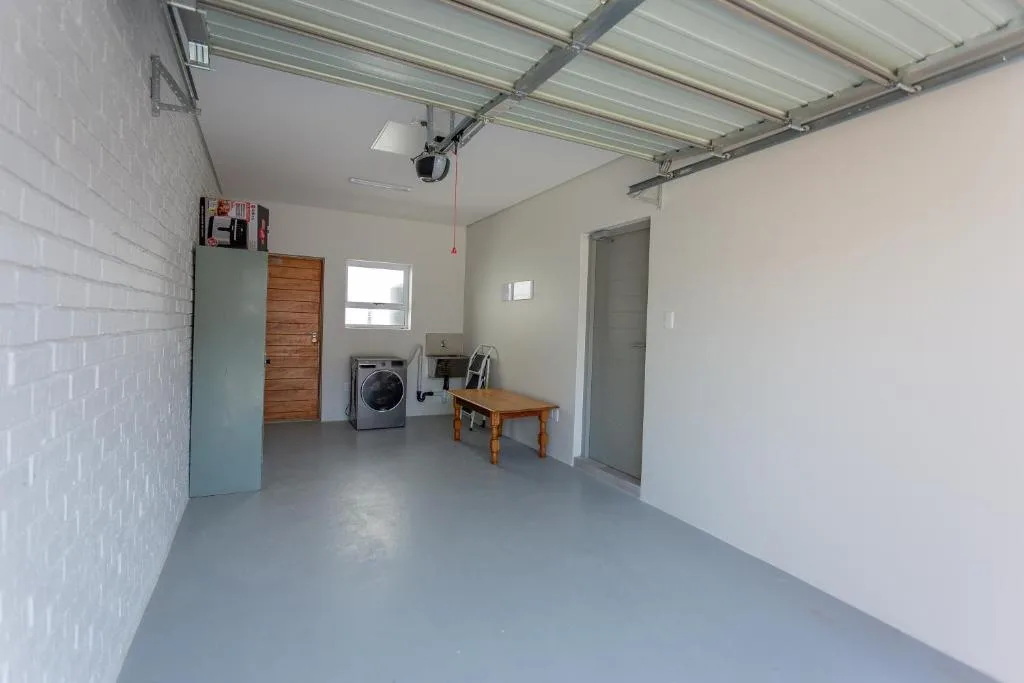 Utility room with washing machine, wooden door, and polished concrete flooring