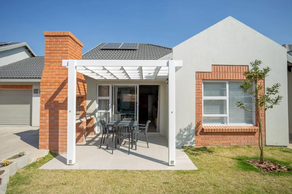 Modern white and brick townhouse with pergola patio and manicured garden