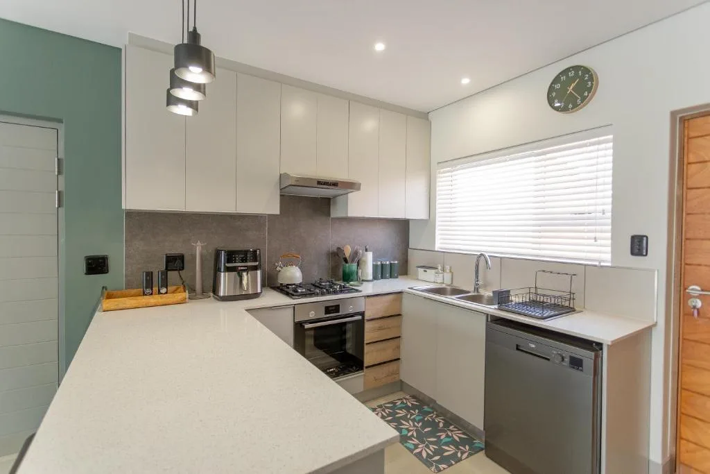 Modern kitchen with white cabinetry, stainless steel appliances, and stone countertops